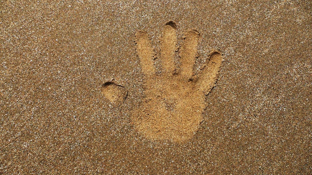 Abruck einer Hand in hellem Sandstrand