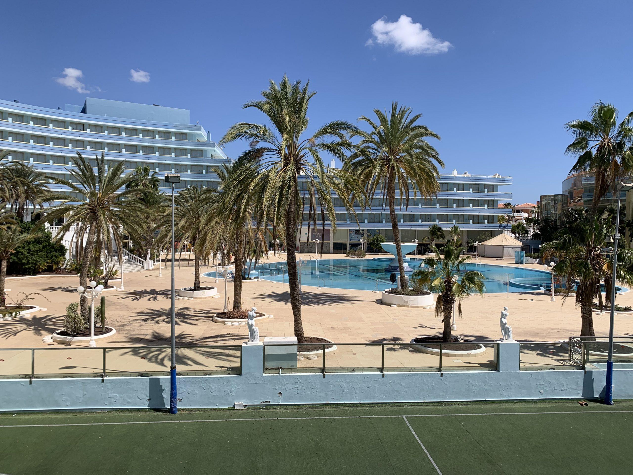 Ein großes mehrstöckiges Hotel mit Pool und Palmen auf Teneriffa